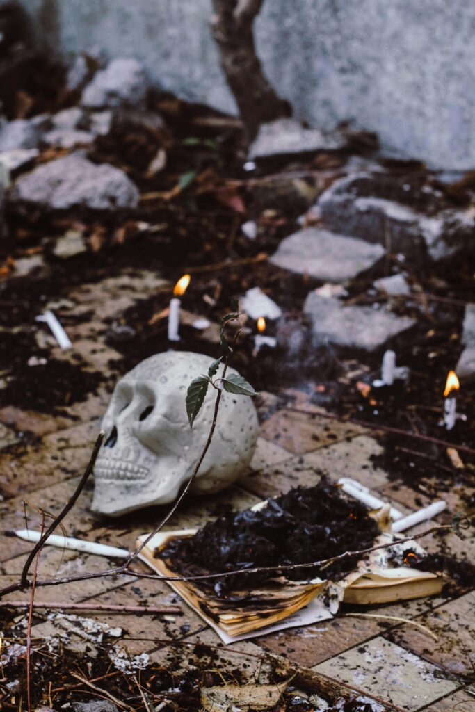 pexels-photo-3058824-3058824 A spooky setup with a skull, burnt book, and candles for a Halloween vibe.